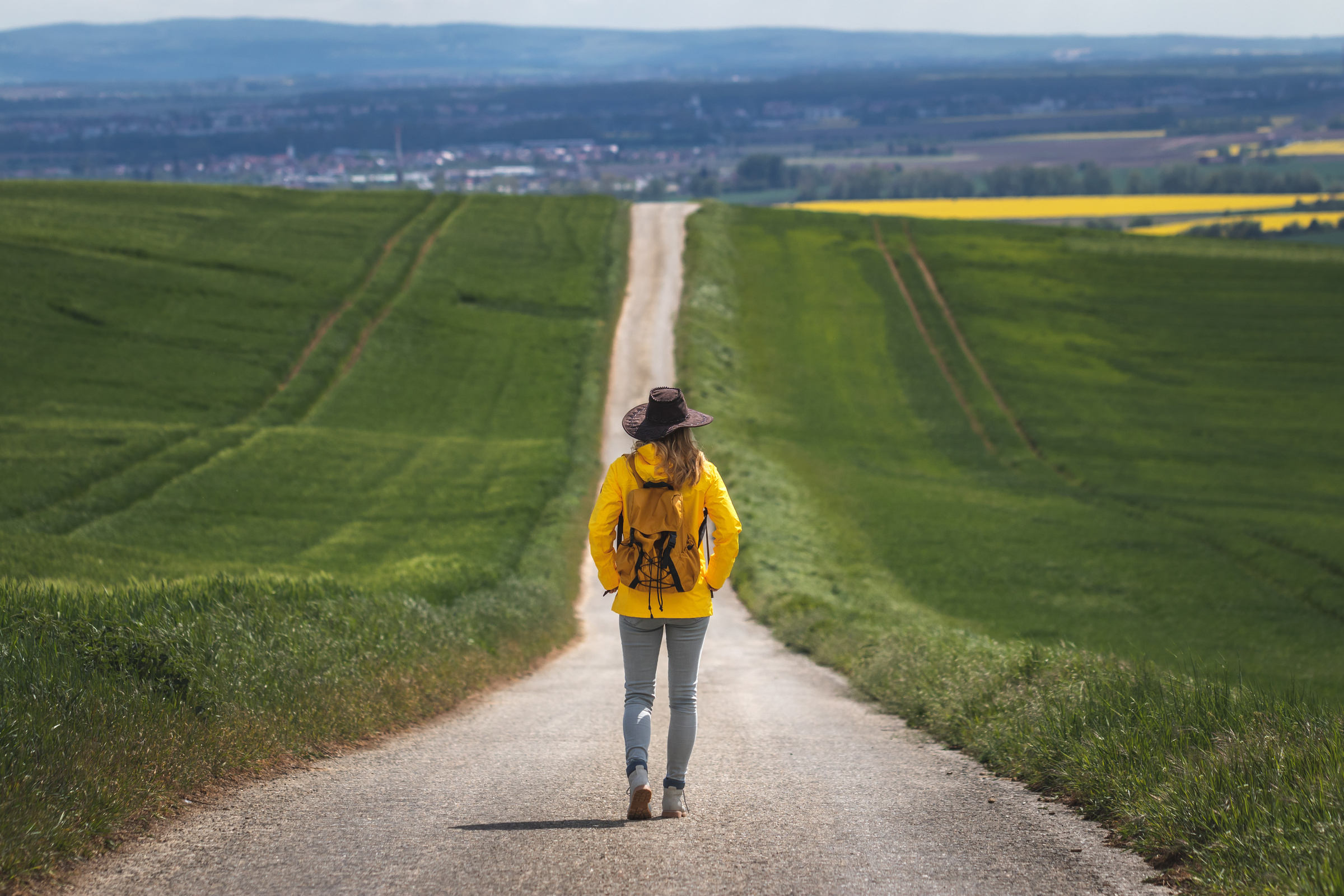 Long journey. Hiking woman walking on empty road